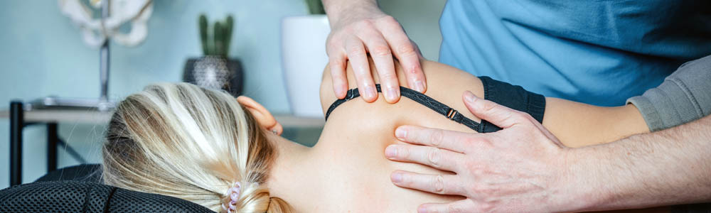 Young woman laying on her side, facing away from the camera; close-up of practitioner's hands working on her shoulder and upper back Young woman laying on her side, facing away from the camera; close-up of practitioner's hands working on her shoulder and upper back